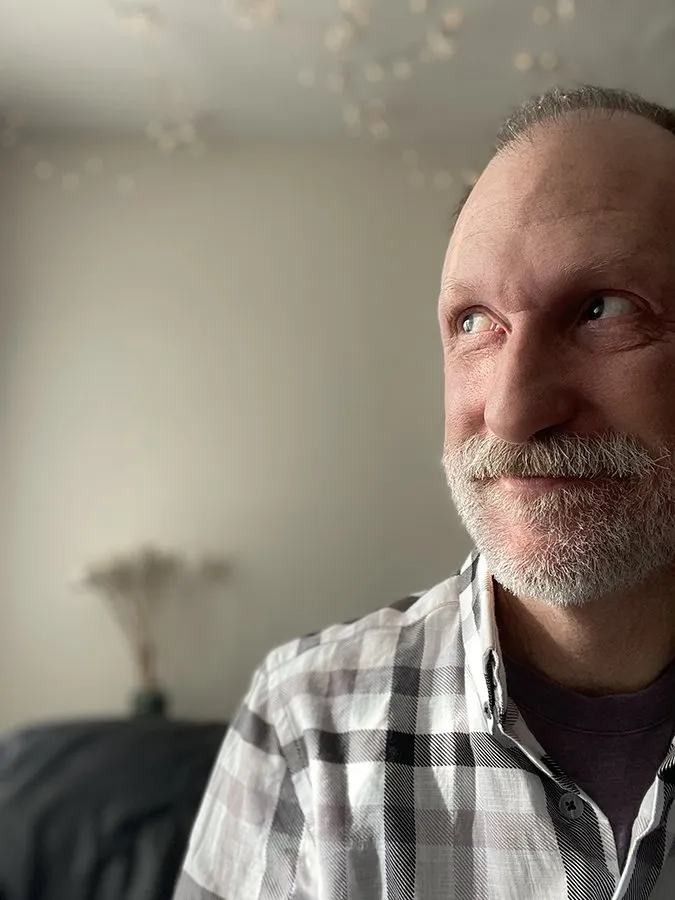 a bearded Raymond Luczak glancing sideways wearing a plaid shirt