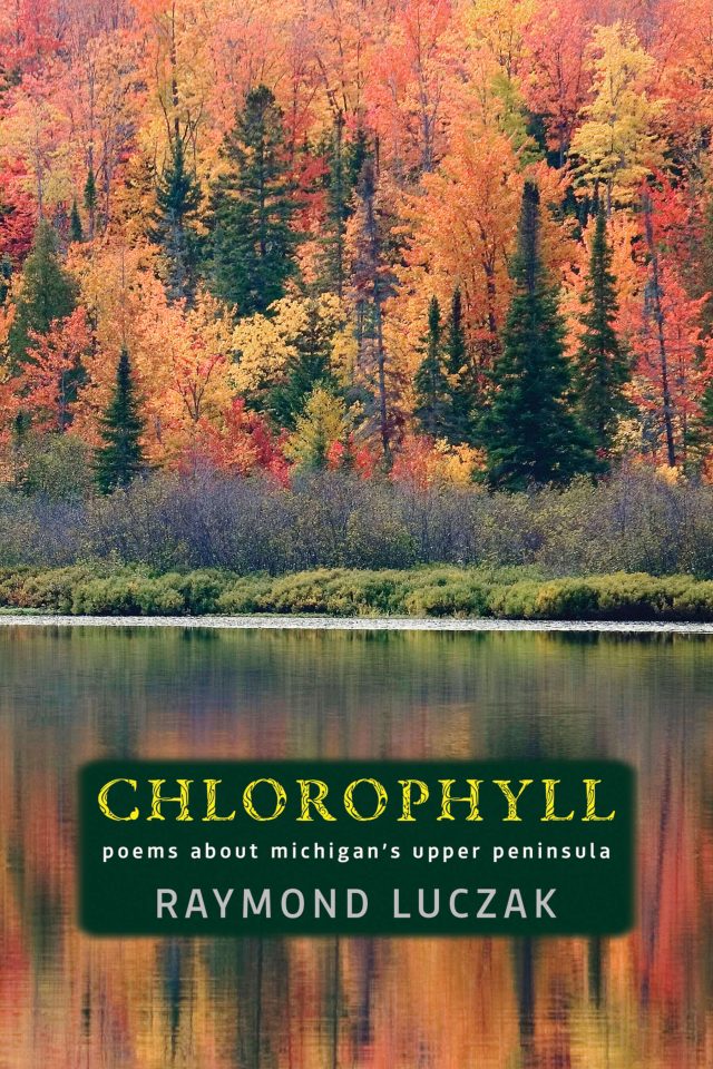 A dense forest in a riot of fall foliage stands before a calm pond mirroring back the colors. Below the trees is a dark green soft-bordered box with the text in yellow and gray: CHLOROPHYLL | poems about michigan's upper peninsula | RAYMOND LUCZAK.